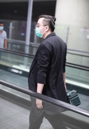 翟天临黑长外套墨镜头顶扎小辫造型别致机场照图片