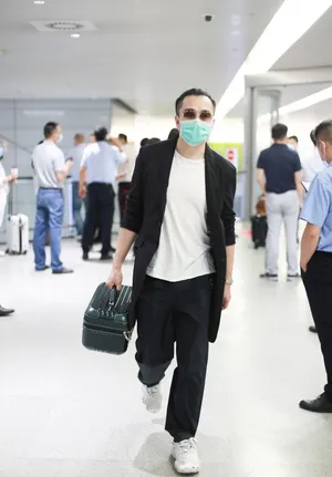 翟天临黑长外套墨镜头顶扎小辫造型别致机场照图片_2