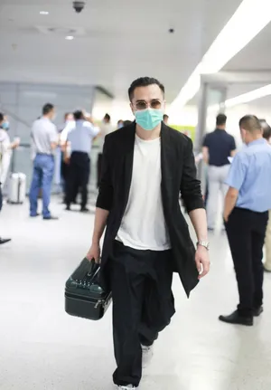 翟天临黑长外套墨镜头顶扎小辫造型别致机场照图片_3