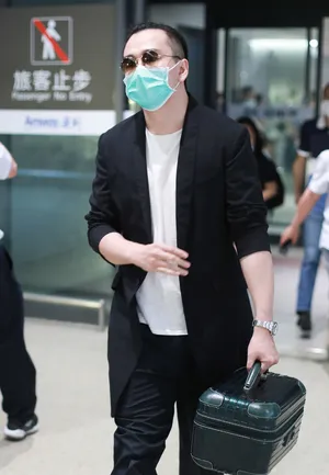 翟天临黑长外套墨镜头顶扎小辫造型别致机场照图片_4