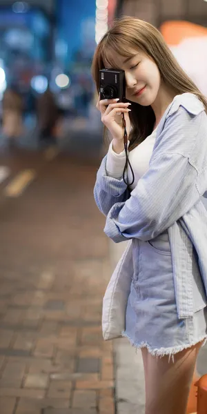 站在街上拿相机拍摄的美女