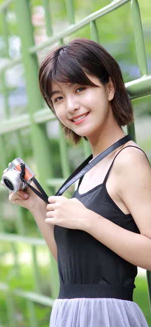 靠着格子栏杆手拿相机穿着吊带上衣的超清纯美女