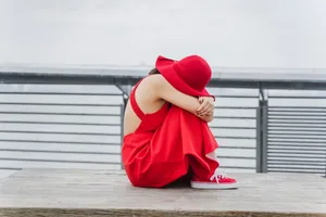 坐在木凳上抱腿的红衣女人图片